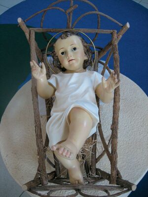 Bambino Gesù benedicente in pasta Madera, con veste, finitura antica, occhi marroni.